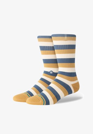 Striped socks in blue, yellow, and cream. Ribbed texture. Features a logo near the ankle and solid toe section. Standard sock height.