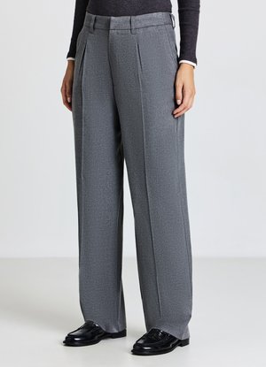 Pantaloni grigi a pieghe con tessuto strutturato, design a gamba larga e passanti per cintura, abbinati a mocassini in pelle nera.