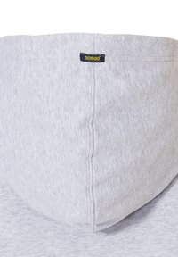 Grijze hoodie van textuurstof, met een trekkoordkap en een klein blauwgele "nomad" label gestikt aan de halsnaad.
