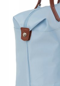 Borsa in nylon azzurro chiaro con una texture liscia, dettagli in pelle marrone, chiusura a zip e manici arrotondati. Design minimalistico.