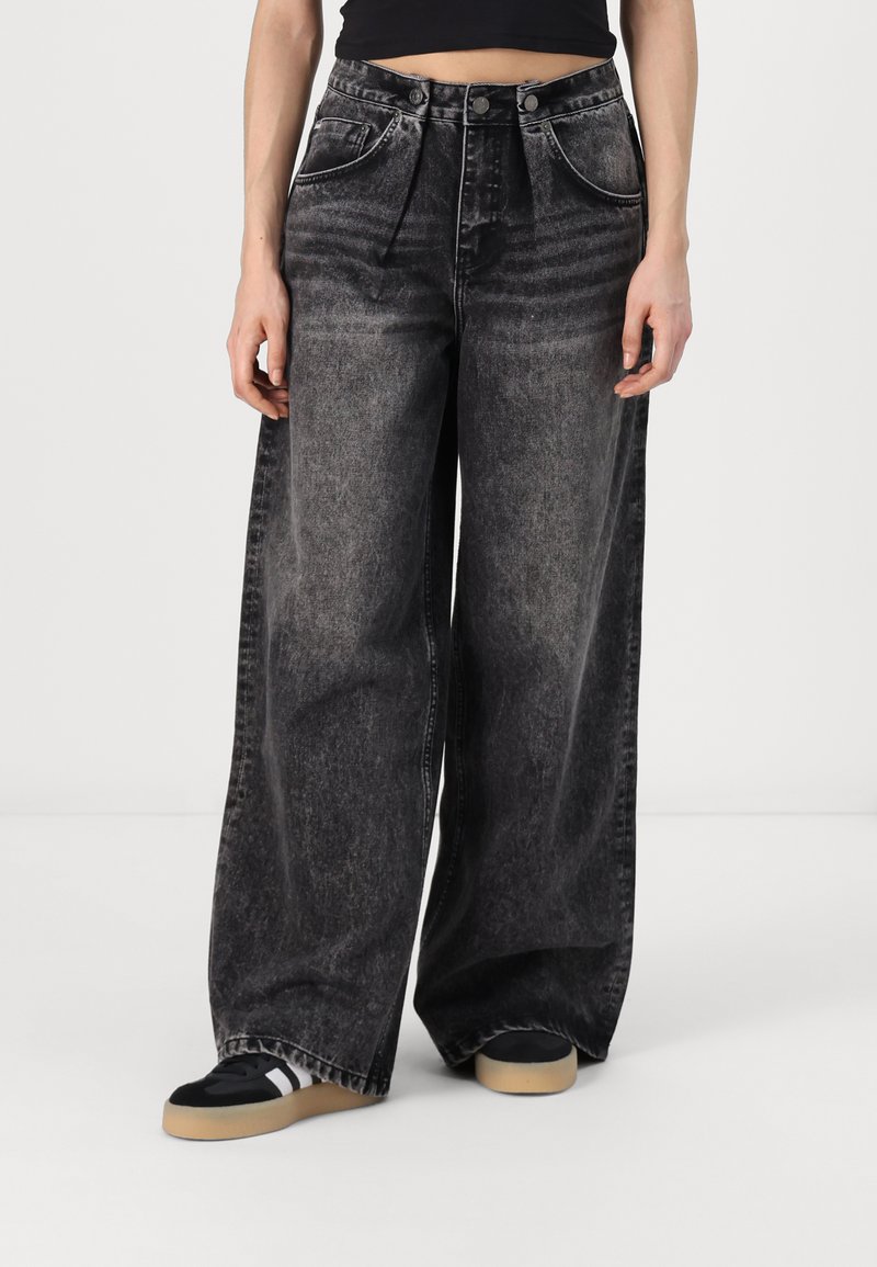 Široké černé džíny z denimu s vybledlým povrchem, předními kapsami, dvoubodovým zapínáním a volným střihem.
