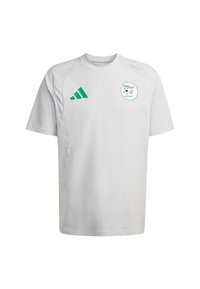 Biały krótki rękaw z zielonymi akcentami, logo Adidas oraz okrągłym emblematem z wzorem piłkarskim i arabskim tekstem.