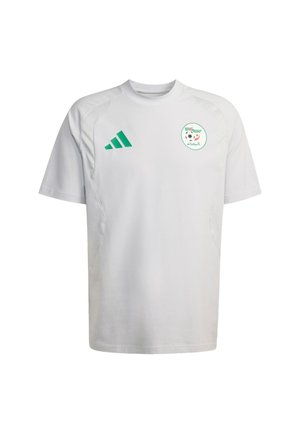 Biały krótki rękaw z zielonymi akcentami, logo Adidas oraz okrągłym emblematem z wzorem piłkarskim i arabskim tekstem.