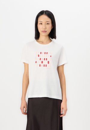 T-shirt en coton blanc avec un imprimé géométrique dans des tons de rouge et de rose. Col rond, manches courtes, coupe décontractée.