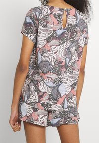 Floral-patterned top and shorts set in pink, gray, and blue, featuring short sleeves and a back keyhole detail with a button closure.