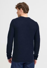 Navy blauwe gebreide trui met lange mouwen, ronde halslijn en ribgebreide manchetten en onderkant. Gladde textuur met een aangesloten ontwerp.