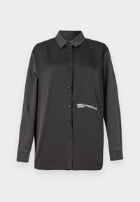 Melnā garo piedurkņu krekls ar pogu aizdari, kontrastējošām džinsa piedurknēm un izšūtu "KARL LAGERFELD JEANS" logotipu uz krūtīm. Gluda tekstūra.