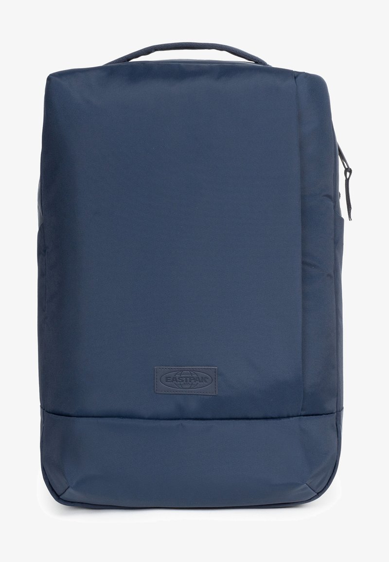 Mochila azul marino hecha de tela duradera, con forma rectangular, asa superior, cremallera y un logotipo de marca destacado en el frente.
