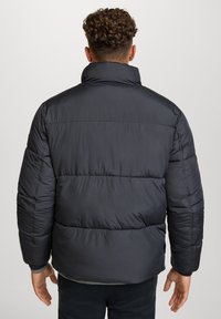 Giubbotto invernale nero con colletto alto, trapuntatura orizzontale e texture liscia e lucida. Progettato per calore e comfort, con polsini elasticizzati.