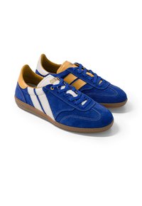 Paire de baskets en daim bleu avec rayures blanches et beiges, lacets bleus et semelles en caoutchouc marron sur fond blanc.