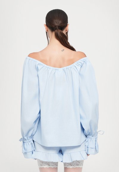 Light blue off-shoulder blouse with gathered neckline and long sleeves. Features ruched cuffs and paired with matching shorts with lace trim.