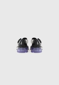 Black footwear with a glossy finish and a chunky, translucent purple sole. Features a strap on the upper portion for secure fit.