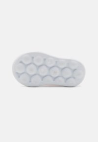 Hvit sneakersåle med et teksturert mønster som har sirkulære puter og spor for grep. Glatt gummimateriale med en semi-blank finish.