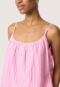 Top de tirantes a rayas rosa y blanca con tirantes finos, un corte holgado y detalles fruncidos en el escote para aportar textura.