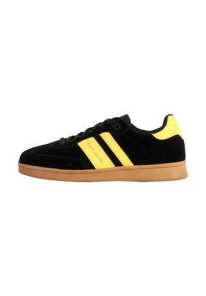 Baskets en daim noir avec rayures et accents jaunes, semelle en caoutchouc naturel, bout arrondi et lacets plats, avec un détail de logo sur le côté.