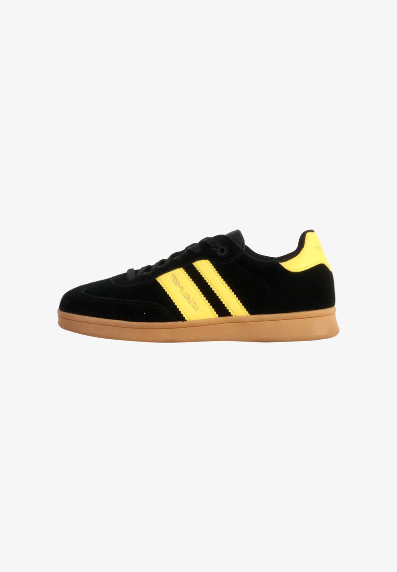 Zapatillas de ante negro con rayas y acentos amarillos, suela de goma, puntera redondeada y cordones planos, con detalle del logo en el lateral.