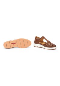 Zapatos de cuero marrón con un diseño trenzado, suela blanca y marrón, correas ajustables y una suela texturizada para mayor agarre.