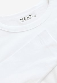 T-shirt a maniche lunghe con collo a giro, in bianco, realizzato in cotone morbido. Presenta una texture liscia e dettagli di cucitura sottili lungo le cuciture.