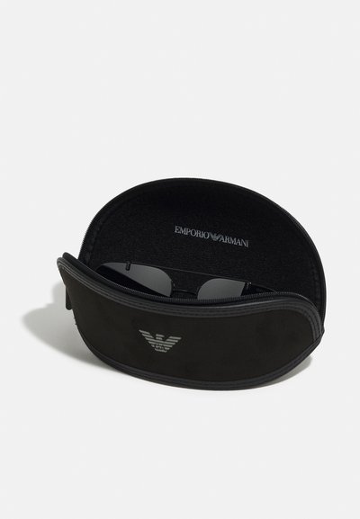 Juodų saulės akinių dėklas su lygiu paviršiumi, užtrauktuku ir minkšta vidine danga. Ant priekio yra iškilus Emporio Armani logotipas.