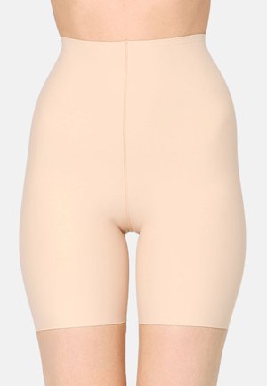 Close-up of a person wearing high-waisted, beige seamless shaping shorts extending to mid-thigh.