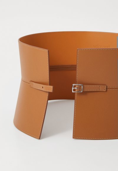 Ceinture en cuir marron au design large, dotée de deux panneaux avant se fermant avec une petite boucle en argent et de jolis détails de couture.