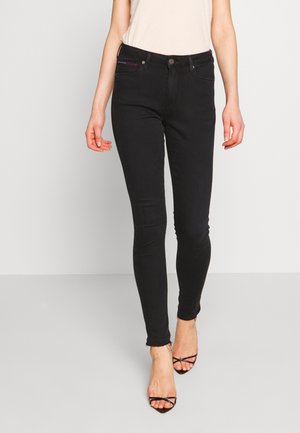 Černé skinny džíny s hladkou texturou, designem pěti kapes a mírně roztrhaným lemem. V kombinaci s černými páskovými podpatky.