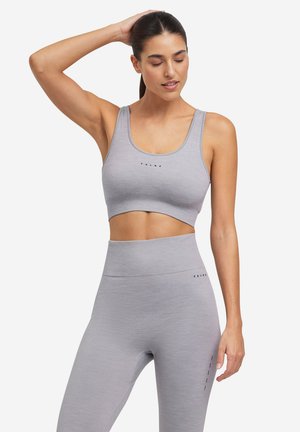 Conjunto deportivo gris que incluye un sujetador deportivo cortado y leggings de cintura alta. Presenta una tela texturizada y un sutil detalle de logo.