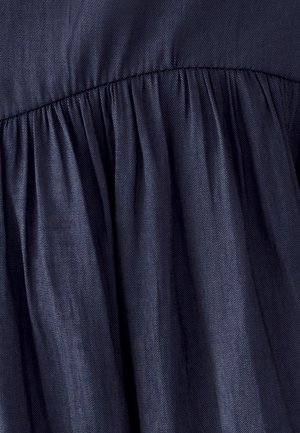 Tissu bleu foncé avec un motif de tissage diagonal rassemblé le long d'une couture cousue, créant des plis doux et une texture.