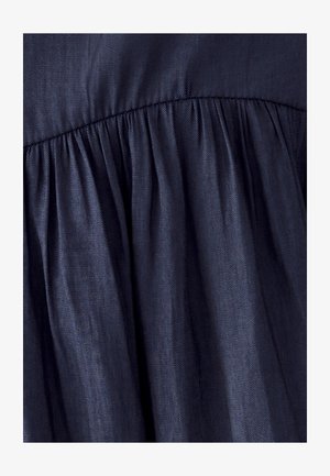 Tissu bleu foncé avec un motif de tissage diagonal rassemblé le long d'une couture cousue, créant des plis doux et une texture.