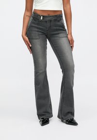 Hallid laiendatud teksad, millel on vormis vöökoht, ees taskud ja kaks nuppu. Tekstureeritud kangas omab tumedast helehallini ulatuvat gradienti.