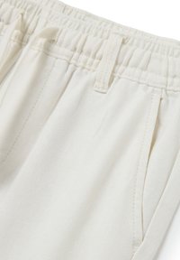 Lichtbeige sportieve broek met een elastische tailleband, zijzakken en een zachte, gestructureerde stofafwerking. Bevat stiksel details.