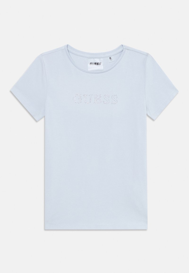 T-shirt bleu clair à manches courtes en coton doux. Il possède un col arrondi et le mot "GUESS" en ornementations en cristaux sur le devant.