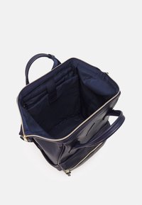 Sac en cuir marine avec fermeture éclair dorée, dispose d'un intérieur spacieux et d'une seule poignée. La doublure est en tissu foncé avec de petites poches intégrées.