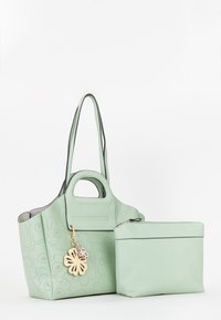 Grøn læderhandtaske med blomstermønster i perforeringerne, dobbelthåndtag, sort trim og en aftagelig matchende pung med lynlås.