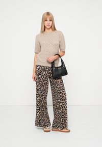 Beži kootud lühikeste varrukatega sviiter, laiad leopardimustrilised püksid ja väike must käekott hõbedaste detailidega. Tekstureeritud kangas ja lõtv lõige.