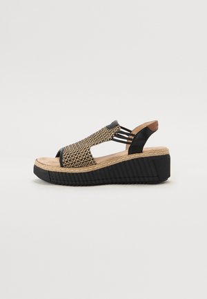 Sandale à talon compensé avec une sangle synthétique noire, un dessus tissé couleur tan et une semelle noire texturée et striée. La semelle intérieure en liège offre un confort supplémentaire.