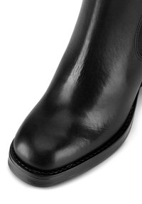 Čierne kožené členkové topánky s lesklým povrchom, zaoblenou špičkou a pevným čiernym podpätkom s viditeľným šitím.