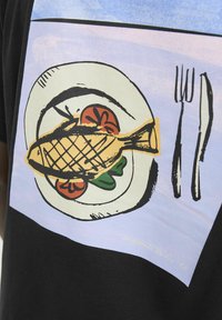 Sort t-shirt med et grafisk motiv af en fisk på en tallerken med grøntsager, omgivet af en lys blå baggrund, samt illustrationer af gaffel og kniv.