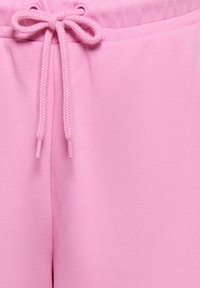 Gros plan sur un short en tissu rose avec une taille à cordon noué et une texture lisse.
