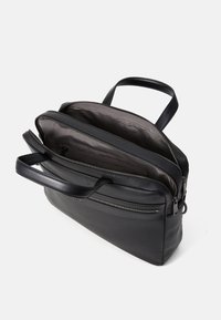 Sacoche pour ordinateur portable en cuir noir avec deux compartiments zippés, des poignées supérieures et une poche avant. Texture lisse et design minimaliste.