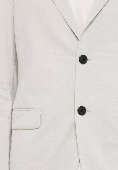Helle graue Leinenjacke mit schmaler Passform, ausgestattet mit zwei schwarzen Knöpfen und einer dezenten Textur. Enthält eine einzelne Brusttasche und Revers.