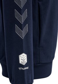 Navy Sweatshirt mit strukturiertem Stoff, diagonalem Streifenmuster in Weiß auf dem Ärmel und logo an der Unterseite.