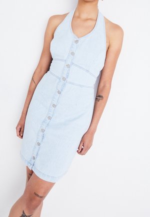 Robe en denim bleu clair avec un design à col halter, fermeture à boutons sur le devant, taille cintrée et ourlet au niveau des genoux. Présente une texture subtile et un style décontracté.