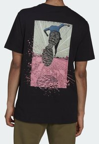 Černé bavlněné tričko s grafickým potiskem na zádech – silueta běžce, růžové skvrny a branding "adidas ADVENTURE".