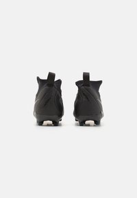 Bottes de football noires au design épuré, avec un col haut, des languettes de traction et une tige synthétique texturée. Présente un logo Nike bien visible et des semelles à crampons.