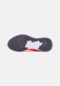 La semelle extérieure de la chaussure présente une surface texturée gris foncé avec des motifs ovales, une semelle intermédiaire blanche contrastante et une forme lisse et arrondie.