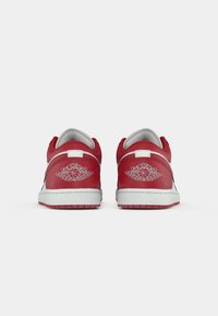Par de sapatilhas Air Jordan vermelhas e brancas visto de trás, mostrando o logótipo das asas Air Jordan nos calcanhares.