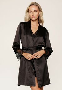 Robe en satin noir avec des accents en dentelle sur les manches, à l'avant ouvert, ceinturée à la taille, design mi-long, texture douce et apparence minimaliste.