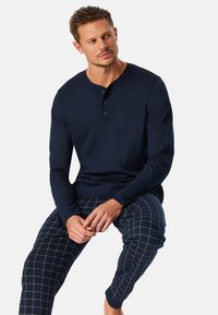 Námořnický dlouhý rukáv henley tričko se třemi knoflíky, kombinované s kostkovanými pyžamovými kalhotami v námořnické a béžové barvě. Měkký bavlněný materiál.