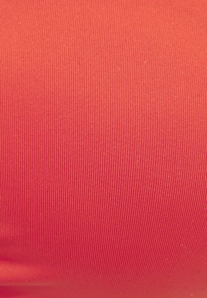 Tekstureeritud punase kangatüübi lähedalt, millel on peente vertikaalsete soonte muster.